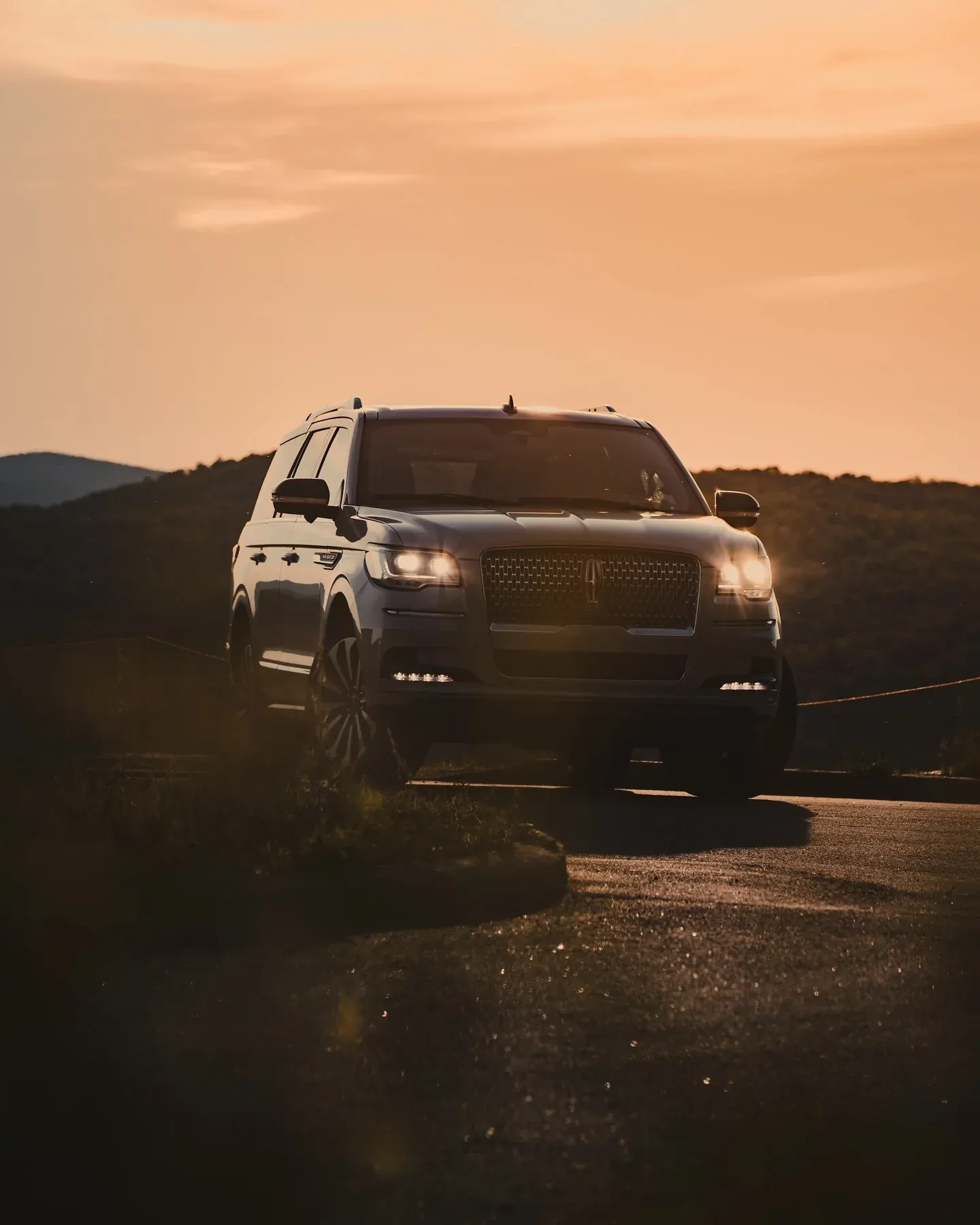 SUV with its headlights on at sunset