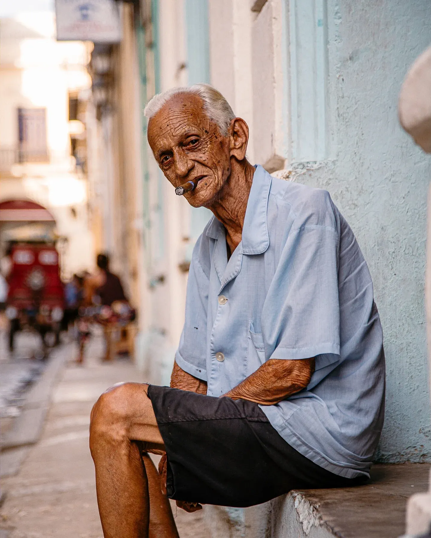 Older man smoking a cigar on a doorstep