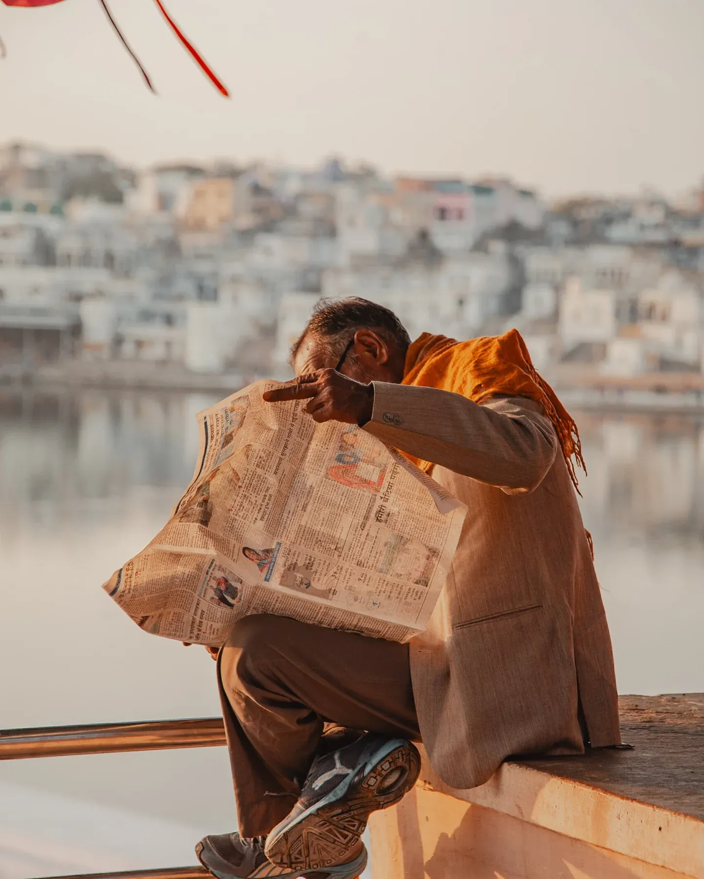 Man reading a newspaper by a lake