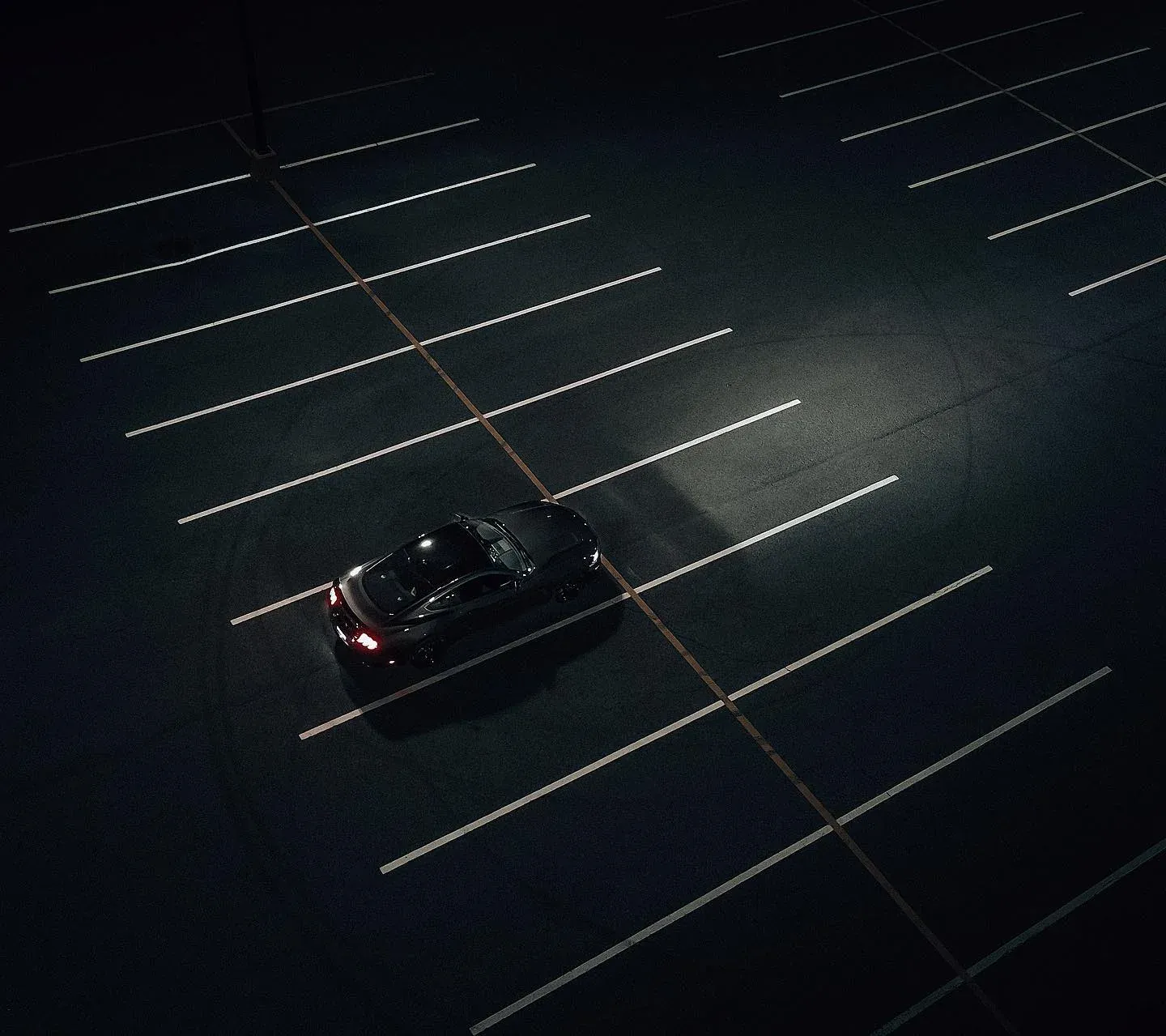 Sports car alone in a dark parking lot, from above