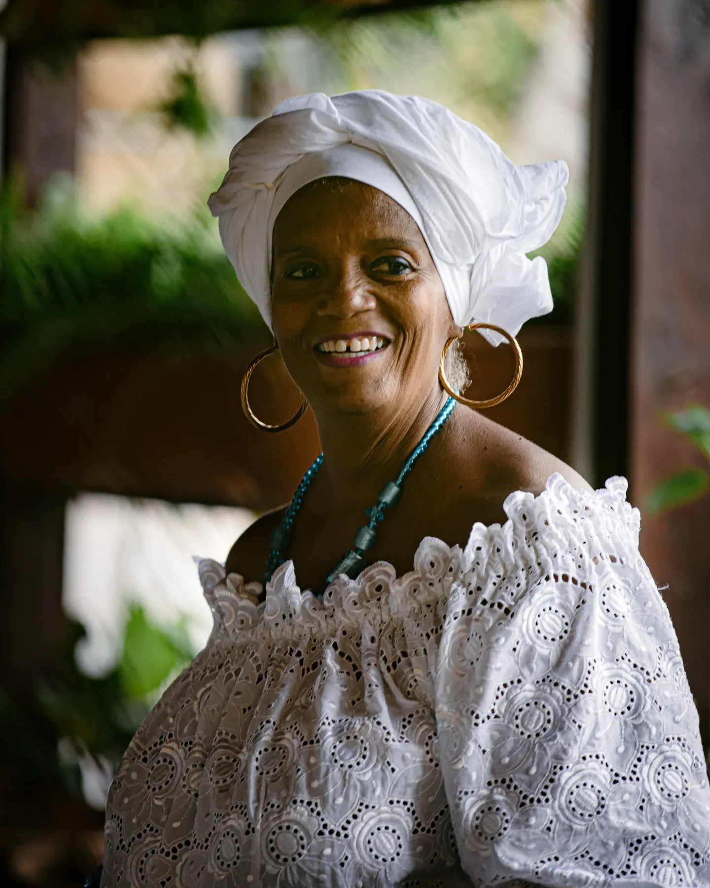 Smiling woman in a white headwrap and lace blouse