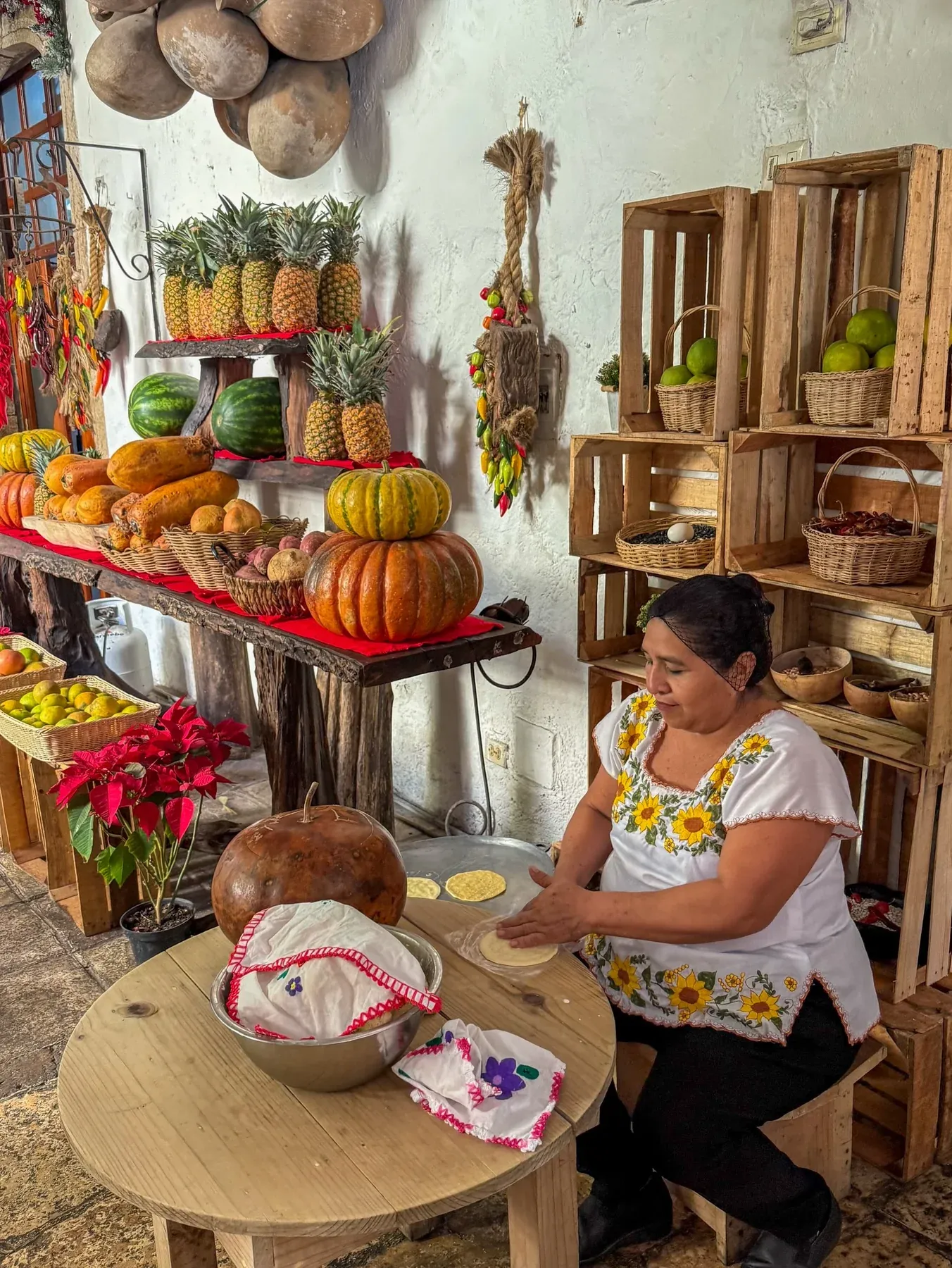 Woman making tortillas beside a fruit stall