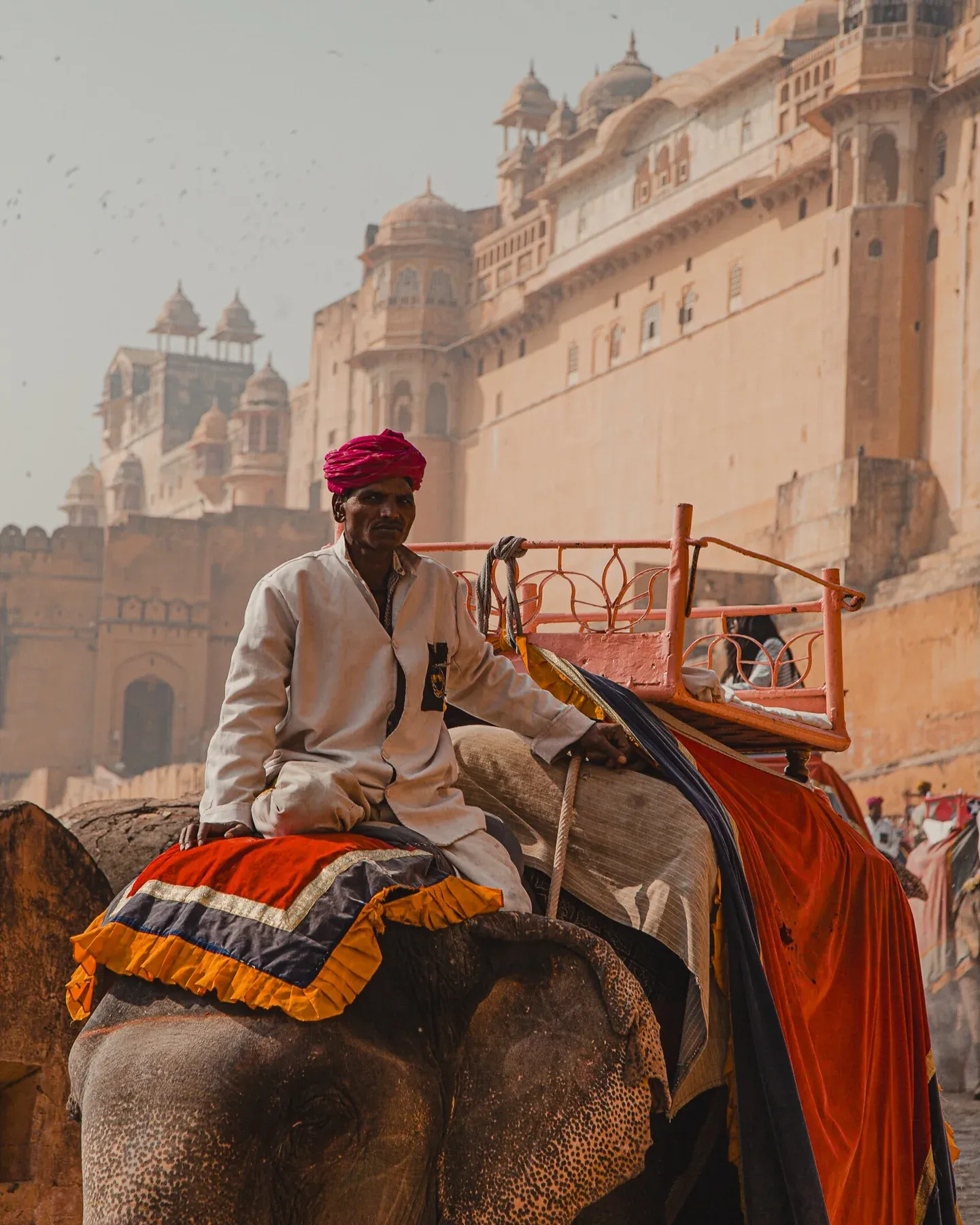 Mahout riding an elephant below a fort